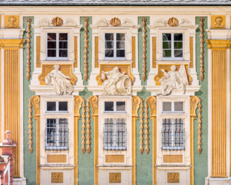 Schloss Bruchsal - Südliche Orangerie / Kavaliersbau - Von Außen - Von Norden - Blick vom Gartenbalkon auf die Nordfassade der Orangerie mit drei Allegorien bzw. Figuren (in der Mitte "Diogenes" (antiker griechischer Philosoph, mit Laterne und Fass), links und rechts zwei antike Philosophen) (Fassade der Orangerie ursprünglich gemalt von Giovanni Francesco Marchini, zwischen 1732 und 1737, restauriert von Josef Mariano Kitschker, zwischen 1900 und 1910, erneut restauriert von Klaus Siller (Fassadenmalerei) und  Walter Maschke (Allegorien), 1976) (aufgenommen im Juli 2021, am frühen Nachmittag)