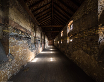 Schloss Bruchsal - Finsterer Gang / Verbindungsgang - Von Innen - Von Süden - Blick nach Norden in das obere Stockwerk und den Dachstuhl des Finsteren Gangs; die Wand hinten grenzt an die Hofkirche (aufgenommen im Juli 2021, am späten Vormittag) Schloss Bruchsal - Finsterer Gang / Verbindungsgang - Von Innen - Von Süden - Blick nach Norden in das obere Stockwerk und den Dachstuhl des Finsteren Gangs; die Wand hinten grenzt an die Hofkirche (aufgenommen im Juli 2021, am späten Vormittag)