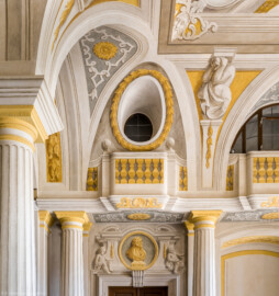 Schloss Bruchsal - Hauptbau / Corps de Logis - Erdgeschoss - Eingangshalle / Intrada - Nordwestecke - Von Süden - Blick von der südwestlichen Tür nach Norden auf den westlichen oberen Teil der Nordwand, die Türbekronung, das Gesims, die Balustrade und Fenster; zwischen den beiden linken Säulen befindet sich der nördliche Haupttreppenaufgang; hinter den Fenstern verläuft ein Dienergang, der vom nördlichen in das südliche Zwischengeschoss führt (Malereien ursprünglich von Giovanni Francesco Marchini, restauriert von Hermenegild Peiker) (aufgenommen im September 2021, am späten Vormittag) Schloss Bruchsal - Hauptbau / Corps de Logis - Erdgeschoss - Eingangshalle / Intrada - Nordwestecke - Von Süden - Blick von der südwestlichen Tür nach Norden auf den westlichen oberen Teil der Nordwand, die Türbekronung, das Gesims, die Balustrade und Fenster; zwischen den beiden linken Säulen befindet sich der nördliche Haupttreppenaufgang; hinter den Fenstern verläuft ein Dienergang, der vom nördlichen in das südliche Zwischengeschoss führt (Malereien ursprünglich von Giovanni Francesco Marchini, restauriert von Hermenegild Peiker) (aufgenommen im September 2021, am späten Vormittag)