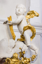 Bruchsal - Peterskirche / St. Peter - Von Innen / Von Westen - Blick auf den obersten Putto am Deckel der Kanzel (Kanzel geschaffen von Johann Michael Feuchtmayer, 1756) (aufgenommen im März 2022, am Nachmittag, nach der Renovierung, nach der Renovierung)