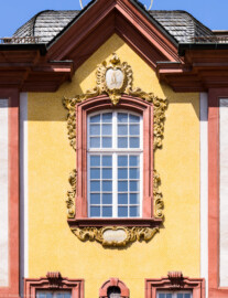 Schloss Bruchsal - Südlicher Verbindungsbau - Von Osten / Hofseite - Blick vom Ehrenhof auf das obere zentrale Fenster; Inschriften der Kartuschen, oben "F C", unten "anno 1974" (aufgenommen im April 2022, um die Mittagszeit)