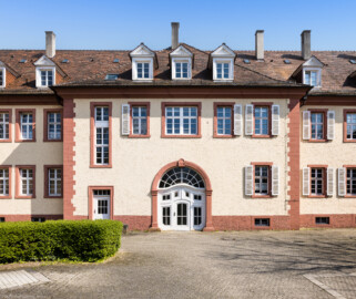 Schloss Bruchsal - Landhospital / Seminarbau - Innenhof, Westwand, Mittelrisalit - Von Außen - Von Westen - Blick nach Osten auf den Mittelrisalit mit dem Durchgang zur Schönbornstraße (aufgenommen im April 2022, am Nachmittag)