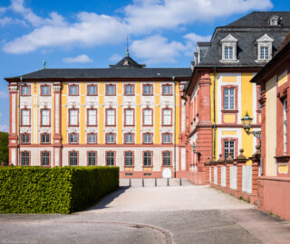 Schloss Bruchsal - Hauptbau / Corps de Logis - Von Außen - Von Süden - Blick von der Hofapotheke auf die Südfassade des Hauptbaus, rechts die Hofapotheke, dahinter die Hofkirche (aufgenommen im April 2022, am späten Nachmittag)
