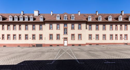 Schloss Bruchsal - Großer Dienerbau / Finanzamt - Von Außen - Mitteltrakt - Von Osten - Blick nach Westen auf die Ostfassade und den Mittelrisalit des Mitteltrakts; in der Mitte der Durchgang zur Schönbornstraße (aufgenommen im Juli 2022, um die Mittagszeit) Schloss Bruchsal - Großer Dienerbau / Finanzamt - Von Außen - Mitteltrakt - Von Osten - Blick nach Westen auf die Ostfassade und den Mittelrisalit des Mitteltrakts; in der Mitte der Durchgang zur Schönbornstraße (aufgenommen im Juli 2022, um die Mittagszeit)