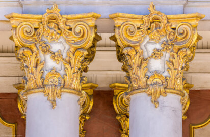 Schloss Bruchsal - Von Außen - Hauptbau - Von Osten / Hofseite - Mittelrisalit / Balkon / Direkt links der Mitte - Zwei Kapitelle, geschaffen von Joachim Günther (aufgenommen im Juli 2022, am Nachmittag)