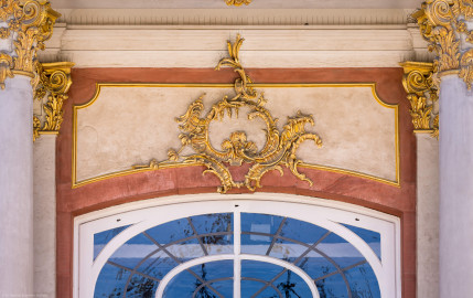 Schloss Bruchsal - Von Außen - Hauptbau / Corps de Logis - Von Osten / Hofseite - Mittelrisalit / Eingang - Blick auf einen Bereich oberhalb der Eingangstür mit den Stuckverzierungen (aufgenommen im Juli 2022, am Nachmittag) Schloss Bruchsal - Von Außen - Hauptbau / Corps de Logis - Von Osten / Hofseite - Mittelrisalit / Eingang - Blick auf einen Bereich oberhalb der Eingangstür mit den Stuckverzierungen (aufgenommen im Juli 2022, am Nachmittag)