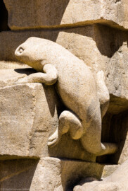 Schloss Bruchsal - Schlossgarten - Hauptachse, Nordseite, 4. Skulptur von Osten - Echsenartige Figur (links unten) der Skulptur "Das Feuer" aus dem Skulpturenensemble "Vier Elemente" (Kopie von Hans Volker Dursy; Original gehauen 1761 von Joachim Günther, befindet sich im Gartensaal des Hauptbaus) (aufgenommen im Juli 2022, am Nachmittag)