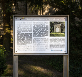 Bruchsal - Peterskirche / St. Peter - Nördliches Schiff, Westseite - Von Außen - Von Westen - Hinweistafel auf einen Gedenkstein für die Bruchsaler Opfer der Badischen Revolution 1848/1849 (Namen auf dem Gedenkstein: Josef Killes, Karl Belgan, Franz Koser, G. Speichler, Joh. Ferg und Peter Lacher) (aufgenommen im August 2022, am frühen Abend) Bruchsal - Peterskirche / St. Peter - Nördliches Schiff, Westseite - Von Außen - Von Westen - Hinweistafel auf einen Gedenkstein für die Bruchsaler Opfer der Badischen Revolution 1848/1849 (Namen auf dem Gedenkstein: Josef Killes, Karl Belgan, Franz Koser, G. Speichler, Joh. Ferg und Peter Lacher) (aufgenommen im August 2022, am frühen Abend)