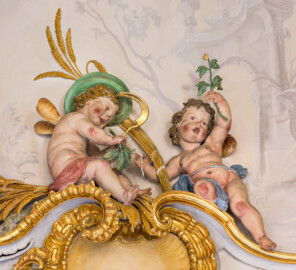 Schloss Bruchsal - Hauptbau / Corps de Logis - Beletage - Marmorsaal / Kaisersaal - Nordwestecke, oben, Stuckfeld - Von Südosten - Blick auf zwei Putti als allegorische Darstellung des Sommers (Stuckaturen ursprünglich von Johann Michael Feichtmayr) (aufgenommen im August 2022, am frühen Nachmittag) Schloss Bruchsal - Hauptbau / Corps de Logis - Beletage - Marmorsaal / Kaisersaal - Nordwestecke, oben, Stuckfeld - Von Südosten - Blick auf zwei Putti als allegorische Darstellung des Sommers (Stuckaturen ursprünglich von Johann Michael Feichtmayr) (aufgenommen im August 2022, am frühen Nachmittag)