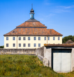 Bad Schönborn / Bad Mingolsheim - Schloss Kislau - Hauptbau - Von Osten - Blick vom Landgraben auf den Hauptbau und die originale Umgebungsmauer, vorne rechts ein neuerer Zugang; hinter den beiden Fenstern ganz links im Erdgeschosss (untere Fensterreihe) befindet sich das Schlafzimmer, rechts davon hinter zwei Fenstern das Badezimmer des Fürstbischofs (aufgenommen im August 2022, um die Mittagszeit)