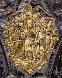 Bruchsal - Peterskirche / St. Peter - Chor - Ewig-Licht-Ampel - Blick auf eines der drei Medaillons der Ewig-Licht-Ampel: der Hl. Laurentius mit dem Rost (Ampel im Barock-Stil, 1962/63 erworben) (aufgenommen im August 2022, am frühen Nachmittag)