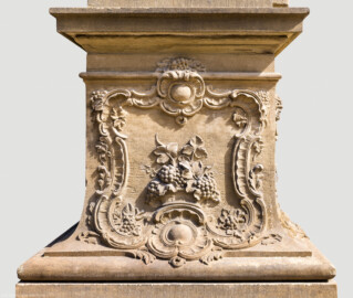 Schloss Bruchsal - Garten - Hauptachse, Nordseite, 2. Skulptur von Osten - Südseite / Frontseite des Sockels der Skulptur "Der Herbst" aus dem Skulpturenensemble "Vier Jahreszeiten" (Kopie; Original gehauen 1759 von Joachim Günther, befindet sich im Harvard Art Museum / Fogg Museum) (aufgenommen im August 2022, am späten Vormittag)