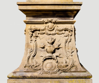 Schloss Bruchsal - Schlossgarten - Hauptachse, Nordseite, 4. Skulptur von Osten - Ostseite / rechte Seite des Sockels der Skulptur "Das Feuer" aus dem Skulpturenensemble "Vier Elemente" (Kopie; Original gehauen 1761 von Joachim Günther, befindet sich im Gartensaal des Hauptbaus) (aufgenommen im August 2022, um die Mittagszeit)