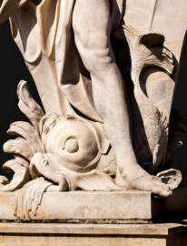 Schloss Bruchsal - Schlossgarten - Hauptachse, Nordseite, 3. Skulptur von Osten -Fischartige Figur (unten Mitte) der Skulptur "Das Wasser" aus dem Skulpturenensemble "Vier Elemente" (Kopie von Hans Volker Dursy; Original gehauen 1761 von Joachim Günther, befindet sich im Gartensaal des Hauptbaus) (aufgenommen im August 2022, am Nachmittag)
