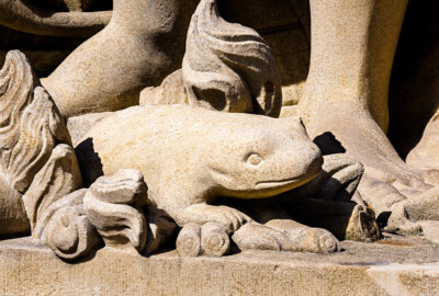 Schloss Bruchsal - Schlossgarten - Hauptachse, Nordseite, 4. Skulptur von Osten - Salamanderartige Figur (unten Mitte) der Skulptur "Das Feuer" aus dem Skulpturenensemble "Vier Elemente" (Kopie von Hans Volker Dursy; Original gehauen 1761 von Joachim Günther, befindet sich im Gartensaal des Hauptbaus) (aufgenommen im August 2022, am Nachmittag)