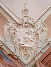 Bad Schönborn / Bad Mingolsheim - Schloss Kislau - Hauptbau - Von Innen - Schlafzimmer - Decke, Nordosttecke - Blick nach oben auf die Stuckverzierung der nordöstlichen Ecke der Decke des Schlafzimmers; im Zentrum ein spielendes Kind und allegorische Andeutungen der Jahreszeit Frühling und des Elements Wasser; Stuckverzierungen erstellt vor 1770 von Joachim Günther (1720-1789) (aufgenommen im September 2022, am späten Vormittag)
