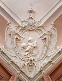 Bad Schönborn / Bad Mingolsheim - Schloss Kislau - Hauptbau - Von Innen - Schlafzimmer - Decke, Südosttecke - Blick nach oben auf die Stuckverzierung der südöstlichen Ecke der Decke des Schlafzimmers; im Zentrum ein spielendes Kind und allegorische Andeutungen der Jahreszeit Sommer und des Elements Luft; Stuckverzierungen erstellt vor 1770 von Joachim Günther (1720-1789) (aufgenommen im September 2022, am späten Vormittag)