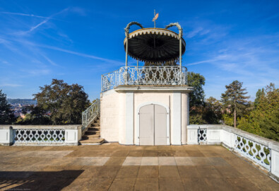 Bruchsal - Belvedere / Schießhaus - Von oben - Nördlicher Pavillon - Von Osten - Blick von der Terrasse nach Westen auf den nördlichen Pavillon; links die Treppe hoch zur Plattform, oben der Baldachin mit Wetterfahne, an der Treppe und auf dem Balkon schmiedeeiserne Gitter (Baldachin, Wetterfahne und Gitter nach zeitgenössischer Chinamode); in der Mitte die Tür zum Wendeltreppe-Abgang in den Raum unter der Terrasse (aufgenommen im Oktober 2022, am späten Vormittag) Bruchsal - Belvedere / Schießhaus - Von oben - Nördlicher Pavillon - Von Osten - Blick von der Terrasse nach Westen auf den nördlichen Pavillon; links die Treppe hoch zur Plattform, oben der Baldachin mit Wetterfahne, an der Treppe und auf dem Balkon schmiedeeiserne Gitter (Baldachin, Wetterfahne und Gitter nach zeitgenössischer Chinamode); in der Mitte die Tür zum Wendeltreppe-Abgang in den Raum unter der Terrasse (aufgenommen im Oktober 2022, am späten Vormittag)