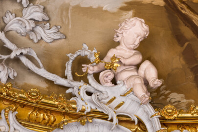 Schloss Bruchsal - Hauptbau / Corps de Logis - Beletage - Marmorsaal / Kaisersaal - Stuckaturzone im unterern Teil der Decke, oberhalb der südöstlichen Doppelsäule - Blick auf einen Putto (Stuck urspünglich von Johann Michael Feuchtmayer dem Jüngeren, rekonstruiert 1962 bis 1969 von Jakob und Josef Schnitzer) (aufgenommen im Februar 2023, am Nachmittag)