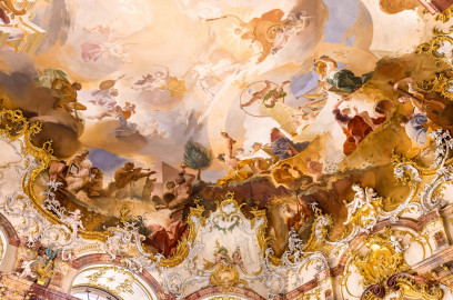 Schloss Bruchsal - Hauptbau / Corps de Logis - Von innen - Beletage - Marmorsaal / Kaisersaal - Decke, nordwestliches Viertel - Von Südosten - Blick nach oben auf die nordwestliche Ecke der Decke - Links oben: verschiedene Götter; links unten: Darstellung der Eitelkeit, mit einer Perlenkette um den Hals und einem Spiegel in der Hand, umgeben von drei Satyrn; rechts ganz oben: der Sonnengott Apoll mit seinem Sonnenwagen über dem Zodiacus (dem Tierkreis); unterhalb des Sonnenwagens: zwei Horen, Göttinnen der Jahreszeiten, Tau aus Krügen gießend; rechts oben: der Weltbaumeister Demogorgon mit Schlangenring als Symbol der Ewigkeit, vor einem Obelisk mit einer Weltkugel oben; rechts unten: das ewige Göttermahl (mit Posaunenbläsern) im Olymp als Symbol für das ewige Bestehen des Bistum Speyer; ganz rechts: Darstellung von Musikern mit Pauke, Cello und Querflöte (Deckenfresko urspünglich gemalt 1754 von Johannes Zick, originalgetreu rekonstruiert 1971 bis 1974 von Wolfram Köberl; Stuck urspünglich von Johann Michael Feuchtmayer dem Jüngeren, rekonstruiert 1962 bis 1969 von Jakob und Josef Schnitzer) (aufgenommen im März 2023, am frühen Nachmittag) Schloss Bruchsal - Hauptbau / Corps de Logis - Von innen - Beletage - Marmorsaal / Kaisersaal - Decke, nordwestliches Viertel - Von Südosten - Blick nach oben auf die nordwestliche Ecke der Decke - Links oben: verschiedene Götter; links unten: Darstellung der Eitelkeit, mit einer Perlenkette um den Hals und einem Spiegel in der Hand, umgeben von drei Satyrn; rechts ganz oben: der Sonnengott Apoll mit seinem Sonnenwagen über dem Zodiacus (dem Tierkreis); unterhalb des Sonnenwagens: zwei Horen, Göttinnen der Jahreszeiten, Tau aus Krügen gießend; rechts oben: der Weltbaumeister Demogorgon mit Schlangenring als Symbol der Ewigkeit, vor einem Obelisk mit einer Weltkugel oben; rechts unten: das ewige Göttermahl (mit Posaunenbläsern) im Olymp als Symbol für das ewige Bestehen des Bistum Speyer; ganz rechts: Darstellung von Musikern mit Pauke, Cello und Querflöte (Deckenfresko urspünglich gemalt 1754 von Johannes Zick, originalgetreu rekonstruiert 1971 bis 1974 von Wolfram Köberl; Stuck urspünglich von Johann Michael Feuchtmayer dem Jüngeren, rekonstruiert 1962 bis 1969 von Jakob und Josef Schnitzer) (aufgenommen im März 2023, am frühen Nachmittag)