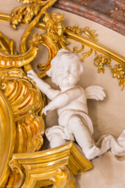 Schloss Bruchsal - Hauptbau / Corps de Logis - Beletage - Marmorsaal / Kaisersaal - Nordwand, oberstes Gesims - Blick auf einen Putto rechts der Mitte (Stuck urspünglich von Johann Michael Feuchtmayer dem Jüngeren, rekonstruiert 1962 bis 1969 von Jakob und Josef Schnitzer) (aufgenommen im März 2023, am Nachmittag)