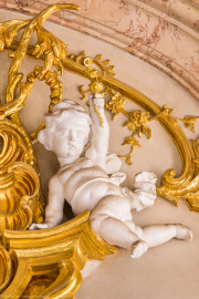 Schloss Bruchsal - Hauptbau / Corps de Logis - Beletage - Marmorsaal / Kaisersaal - Südwand, oberstes Gesims - Blick auf einen Putto rechts der Mitte (Stuck urspünglich von Johann Michael Feuchtmayer dem Jüngeren, rekonstruiert 1962 bis 1969 von Jakob und Josef Schnitzer) (aufgenommen im März 2023, am Nachmittag) Schloss Bruchsal - Hauptbau / Corps de Logis - Beletage - Marmorsaal / Kaisersaal - Südwand, oberstes Gesims - Blick auf einen Putto rechts der Mitte (Stuck urspünglich von Johann Michael Feuchtmayer dem Jüngeren, rekonstruiert 1962 bis 1969 von Jakob und Josef Schnitzer) (aufgenommen im März 2023, am Nachmittag)