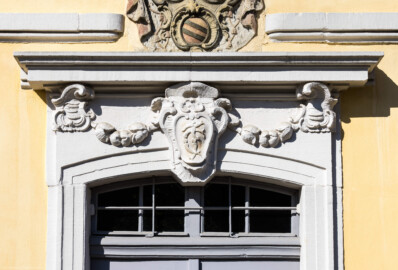 Bad Schönborn / Bad Mingolsheim - Schloss Kislau - Kavalierbau, Mitte, über der zentralen östlichen Tür - Von Osten - Blick auf das Monogram ("FC") von Franz Christoph von Hutten zum Stolzenberg (unten) sowie auf einen Teil des Allianzwappens von Franz Christoph (oben) (aufgenommen im April 2023, am späten Vormittag)