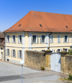 Bad Schönborn / Bad Mingolsheim - Schloss Kislau - Kavalierbau / Stallungsgebäude / Tor zum Ehrenhof - Von Südost - Blick vom mittleren Fenster des 1. Obergeschosses des Küchenbaus nach Nordwest auf den ehemaligen Ehrenhof, den Kavalierbau (Mitte), ein ehemaliges Stallungsgebäude (ganz links) sowie auf die Trennmauer und das Tor zum Ehrenhof (aufgenommen im Juni 2023, um die Mittagszeit)