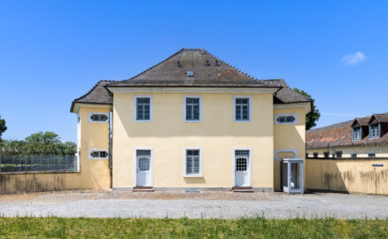 Bad Schönborn / Bad Mingolsheim - Schloss Kislau - Krankenbau - Von Osten - Blick vom ehemaligen Ehrenhof auf den Krankenbau (ehemals Heiduckenbau bzw. Lakaienspeisehaus, in der Mitte) sowie ein ehemaliges Stallungsgebäude (rechts, nach hinten) (aufgenommen im Juni 2023, um die Mittagszeit)