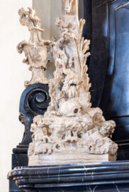 Bruchsal - Peterskirche / St. Peter - Westlicher Chorraum - Doppelgrabdenkmal für Damian Hugo Philipp von Schönborn-Buchheim und für August von Limburg-Stirum -  Von Nordost - Blick auf eine Skulptur mit Christus am Kreuz auf Golgatha, links eine Vase mit Flammen (oben links am Grabdenkmal; Plastik gefertigt von Ferdindanz Diez) (aufgenommen im Mai 2024, am Nachmittag)