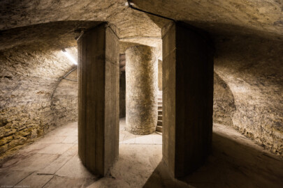 Bad Schönborn / Bad Mingolsheim - Schloss Kislau - Hauptbau - Von Innen - Treppenhaus, Keller - Blick von der Kellerwand auf das Treppenauge in der Bildmitte (der innere Zylinder vom Boden bis zur Decke, um den sich die Treppe windet), rechts und links davon auf Teile der Wendeltreppe sowie im Vordergrund auf Teile des die Treppe umfassenden Zylinders mit Öffnungen vom Boden bis zur Decke (aufgenommen im Mai 2024, am frühen Nachmittag)