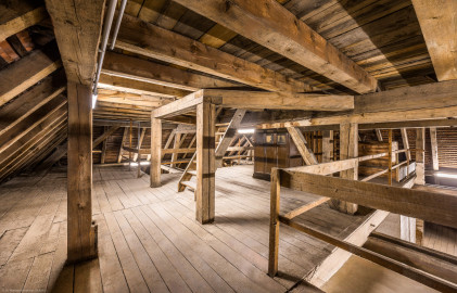 Bad Schönborn / Bad Mingolsheim - Schloss Kislau - Hauptbau - Von Innen - Dachstuhl - Obere Ebene (Ebene 3 von 4) - Von Nordwest - Blick in die obere Ebene des Dachstuhls; die Treppe (in der Bildmitte) führt in die oberste Ebene des Dachstuhls (Ebene 4 von 4) mit dem Zugang zur Turmuhr und zum Glockenturm; rechts der Treppe befindet sich der Schrank für das Uhrwerk der Turmuhr (aufgenommen im Mai 2024, am Nachmittag) Bad Schönborn / Bad Mingolsheim - Schloss Kislau - Hauptbau - Von Innen - Dachstuhl - Obere Ebene (Ebene 3 von 4) - Von Nordwest - Blick in die obere Ebene des Dachstuhls; die Treppe (in der Bildmitte) führt in die oberste Ebene des Dachstuhls (Ebene 4 von 4) mit dem Zugang zur Turmuhr und zum Glockenturm; rechts der Treppe befindet sich der Schrank für das Uhrwerk der Turmuhr (aufgenommen im Mai 2024, am Nachmittag)