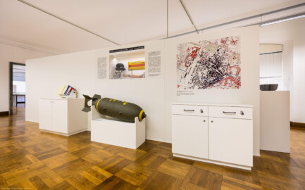 Städtisches Museum Bruchsal - Schloss Bruchsal - Hauptbau / Corps de Logis - Von innen - Westlicher Raum - "Nationalsozialismus und Zweiter Weltkrieg in Bruchsal" - Blick auf die Ostseite der Stellwände in der Mitte des Raums; thematisiert sind hier: Luftschutzobjekte aus Bruchsal und Kriegsschäden in Bruchsal; in der Bildmitte eine 500 Pfund-Sprengbombe  (Raum umgestaltet und fertiggestellt in 2026) (aufgenommen im April 2026, am Nachmittag)