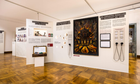 Städtisches Museum Bruchsal - Schloss Bruchsal - Hauptbau / Corps de Logis - Von innen - Westlicher Raum - "Nationalsozialismus und Zweiter Weltkrieg in Bruchsal" - Blick auf die Westseite der Stellwände in der Mitte des Raums; auf den Stellwänden sind hier thematisiert: Die jüdische Gemeinde in Bruchsal ab 1933, Die Progromnacht vom 9./10. November 1938, Jüdische Ritualien aus Bruchsal, Massenmord an der jüdischen Bevölkerung; das Gemälde illustriert den Brand der Synagoge Bruchsal (Maler: Jürgen Spatschke, Datierung: 1992, Öl auf Leinwand) (Raum umgestaltet und fertiggestellt in 2026) (aufgenommen im April 2026, am Nachmittag)