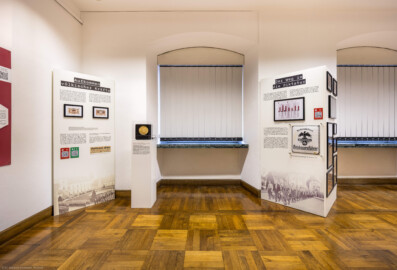 Städtisches Museum Bruchsal - Schloss Bruchsal - Hauptbau / Corps de Logis - Von innen - Westlicher Raum - "Nationalsozialismus und Zweiter Weltkrieg in Bruchsal" - Blick auf Stellwände und Exponate in der Südwestecke des Raums; hier thematisiert: Aufkommen völkischer Kräfte, Nationalsozialistische Propaganda, Der Weg in die Diktatur (Raum umgestaltet und fertiggestellt in 2026) (aufgenommen im April 2026, am späten Nachmittag)