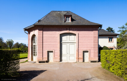 Schloss und Schlossgarten Schwetzingen - Garten - Neue Orangerie - Glashaus - Blick auf die Ostfassade des nachträglich angebauten Glashauses; dahinter das nach Süden hervortretende fünfachsige Treibhaus mit drei großen Türen nach Osten, Südosten und Südwesten (Gesamter Bau: Länge ca. 171 Meter, Breite ca. 10-12 Meter; Bauzeit: 1761-1762, Glashaus angebaut 1770; Architekt: Nicolas de Pigage; umfangreiche Instandsetzung: 1994-1999; Putzflächen bemalt in Freskotechnik, täuschen teilweise ein Scheinmauerwerk vor) (aufgenommen im April 2023, am späten Vormittag) Schloss und Schlossgarten Schwetzingen - Garten - Neue Orangerie - Glashaus - Blick auf die Ostfassade des nachträglich angebauten Glashauses; dahinter das nach Süden hervortretende fünfachsige Treibhaus mit drei großen Türen nach Osten, Südosten und Südwesten (Gesamter Bau: Länge ca. 171 Meter, Breite ca. 10-12 Meter; Bauzeit: 1761-1762, Glashaus angebaut 1770; Architekt: Nicolas de Pigage; umfangreiche Instandsetzung: 1994-1999; Putzflächen bemalt in Freskotechnik, täuschen teilweise ein Scheinmauerwerk vor) (aufgenommen im April 2023, am späten Vormittag)