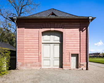 Schloss und Schlossgarten Schwetzingen - Garten - Neue Orangerie - Westseite, Eckpavillon - Blick auf die Westfassade des Pavillons mit der hohen Tür (Gesamter Bau: Länge ca. 171 Meter, Breite ca. 10-12 Meter; Bauzeit: 1761-1762; Architekt: Nicolas de Pigage; umfangreiche Instandsetzung: 1994-1999; Putzflächen bemalt in Freskotechnik, täuschen teilweise ein Scheinmauerwerk vor) (aufgenommen im April 2023, am Nachmittag) Schloss und Schlossgarten Schwetzingen - Garten - Neue Orangerie - Westseite, Eckpavillon - Blick auf die Westfassade des Pavillons mit der hohen Tür (Gesamter Bau: Länge ca. 171 Meter, Breite ca. 10-12 Meter; Bauzeit: 1761-1762; Architekt: Nicolas de Pigage; umfangreiche Instandsetzung: 1994-1999; Putzflächen bemalt in Freskotechnik, täuschen teilweise ein Scheinmauerwerk vor) (aufgenommen im April 2023, am Nachmittag)