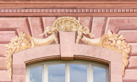 Schloss und Schlossgarten Schwetzingen - Garten - Neue Orangerie - Südseite, Mittelbau - Blick auf eine Schmuckbemalung mit Muschel und Füllhörnern oberhalb eines Fensterbogens (Gesamter Bau: Länge ca. 171 Meter, Breite ca. 10-12 Meter; Bauzeit: 1761-1762; Architekt: Nicolas de Pigage; umfangreiche Instandsetzung: 1994-1999) (aufgenommen im Mai 2023, am späten Vormittag)