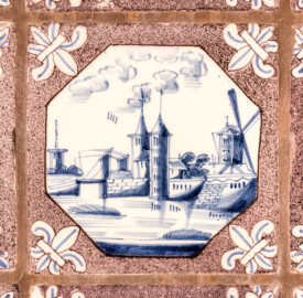 Schloss und Schlossgarten Schwetzingen - Garten - Porzellanhaus - Von innen - Hauptraum, Westwand - Blick auf eine einzelne Landschaftsfliese ("Delfter Porzellan", blaue Bemalung, Format 13 x 13 cm) aus einer Rotterdamer Fayencewerkstatt (Bau: Grundfläche ca. 9 x 9 Meter; Bauzeit: 1762-1764; Architekt: Nicolas de Pigage; Anzahl Fliesen im Porzellanhaus: 1234, davon 1199 Originale; 930 Landschaftsfliesen mit 65 Motiven und 304 Reiterfliesen mit 26 Motiven; Fliesen ursprünglich in der Alten Orangerie verbaut, danach teilweise im Porzellanhaus wiederverwendet; Erwerb von insgesamt 35.000 Fliesen in den Jahren 1723 und 1727) (aufgenommen im Mai 2023, am frühen Nachmittag)