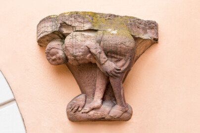 Schloss und Schlossgarten Schwetzingen - Schloss - Mittelbau - Hofseite - Von Osten - Blick auf die Spottfigur rechts des Bogens der Durchfahrt zum Garten; Datierung um 1470/80; Figur vermutlich ehemals als Säulenfuß genutzt; als Groteske streckt die Figur dem Betrachter sein Gesäß zum Spott entgegen (aufgenommen im Mai 2023, um die Mittagszeit) Schloss und Schlossgarten Schwetzingen - Schloss - Mittelbau - Hofseite - Von Osten - Blick auf die Spottfigur rechts des Bogens der Durchfahrt zum Garten; Datierung um 1470/80; Figur vermutlich ehemals als Säulenfuß genutzt; als Groteske streckt die Figur dem Betrachter sein Gesäß zum Spott entgegen (aufgenommen im Mai 2023, um die Mittagszeit)