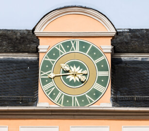 Schloss und Schlossgarten Schwetzingen - Schloss - Mittelbau - Hofseite - Von Osten - Blick auf die zentrale Uhr am Dach; die Zeiger sind aus unbekannten Gründen vertauscht, der große Zeiger zeigt die Stunden, der kleine Zeiger die Minuten an; die Zeiger wurden bis 1968 angetrieben von der alten Turmuhr im Südturm, geschaffen 1763 vom Uhrmacher Johann Jacob Möllinger (1695-1763), der auch das Zifferblatt schuf (aufgenommen im Mai 2023, am Vormittag)