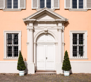 Schloss und Schlossgarten Schwetzingen - Schloss - Nordflügel / Hofkavaliersflügel - Querbau - Von Osten - Blick auf das Portal der Schlosskapelle mit Tympanon, Gesims, Fries, Kapitellen, Säulen und Postamenten (NordFlügel: L-förmig, Länge x Breite Längsbau ca. 50 x 14 Meter, Querbau ca. 15 x 12 Meter; Architekt: Johann Adam Breunig (1660-1727); Fertigstellung: 1710) (aufgenommen im Mai 2023, am Vormittag)