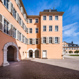 Schloss und Schlossgarten Schwetzingen - Schloss - Mittelbau - Hofseite - Von Süden - Blick auf die Ostfassade (links) und die Südfassade (Mitte) des nördlichen Teils des Mittelbaus; rechts die Südfassade des Nordflügels / Hofdamenflügels (Mittelbau: Länge Westseite ca. 45 Meter, Breite Süd-/Nordseite ca. 38 Meter; Wiederaufbau / Erweiterung: 1698-1717; Architekt: Johann Adam Breunig) (aufgenommen im Mai 2023, am späten Vormittag)
