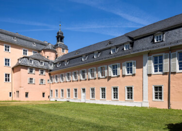 Schloss und Schlossgarten Schwetzingen - Schloss - Mittelbau / Südflügel / Küchenflügel - Von Südwest - Blick auf die Südfassade des Mittelbaus, den Treppenturm, den Südturm mit dem Dachreiter, den Glocken und dem Hemmerscher Fünfspitz (links) sowie auf die Westfassaden des Südflügels und des Küchenflügels (rechts); die fünf linken unteren Fenster und die Tür gehören zum Querbau des Südflügels, die nächsten vier Fenster bis zum Pilaster gehören zum Längsbau des Südflügels, die drei Fenster ganz rechts gehören zum Querbau des Küchenflügels (Südflügel: L-förmig, Länge x Breite Längsbau ca. 50 x 14 Meter, Querbau ca. 15 x 11 Meter; Architekt: Johann Adam Breunig (1660-1727); Fertigstellung: 1710, letzte Renovierung: 2009-2012; Küchenflügel: L-förmig, Länge x Breite Längsbau ca. 75 x 13 Meter, Querbau ca. 25 x 11 Meter; Architekt: Nicolas de Pigage (1723-1796); Fertigstellung: 1761, letzte Renovierung: 2009-2012) (aufgenommen im Mai 2023, am Nachmittag)