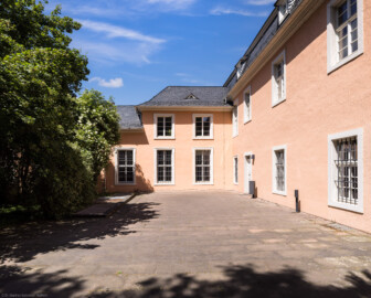 Schloss und Schlossgarten Schwetzingen - Schloss - Verbindungsbau Küchenbau-Zirkelbau / Alte Galerie - Südfassade, östliche Seite - Von Süden - Blick auf die Südfassade des Verbindungsgang zwischen dem Küchenflügel und dem Südlichen Zirkelbau, rechts die Westfassade des Küchenbaus (Verbindungsbau: Länge ca. 45 Meter, Breite ca. 8 Meter; Bauzeit: wohl um 1724; Architekt: unklar, evtl. Alessandro Galli da Bibiena (1686-1748) oder Johann Adam Breunig (1660-1727)) (aufgenommen im Mai 2023, am Nachmittag)