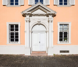 Schloss und Schlossgarten Schwetzingen - Schloss - Südflügel / Hofdamenflügel - Querbau - Von Osten - Blick auf die Ostfassade und das Portal des Querbaus (Südflügel: L-förmig, Länge x Breite Längsbau ca. 50 x 14 Meter, Querbau ca. 15 x 11 Meter; Architekt: Johann Adam Breunig (1660-1727); Fertigstellung: 1710, letzte Renovierung: 2009-2012) (aufgenommen im Juni 2023, am Vormittag)