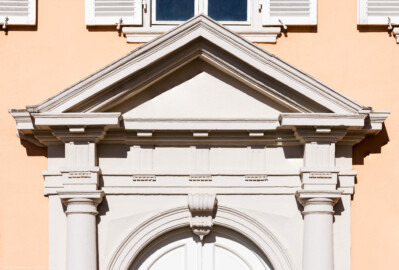 Schloss und Schlossgarten Schwetzingen - Schloss - Nordflügel / Hofkavaliersflügel - Querbau - Von Osten - Blick auf Tympanon, Gesims, Fries und Kapitelle des Portals der Schlosskapelle Nordflügel (NordFlügel: L-förmig, Länge x Breite Längsbau ca. 50 x 14 Meter, Querbau ca. 15 x 12 Meter; Architekt: Johann Adam Breunig (1660-1727); Fertigstellung: 1710) (aufgenommen im Juni 2023, am Vormittag)