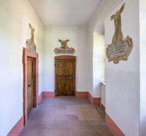 Schloss und Schlossgarten Schwetzingen - Schloss - Nordflügel, Nord-Süd-Teil - Gang zur Schlosskapelle - Von Norden - Blick nach Süden in den Gang zur Kapelle mit den Gemälden zur Erinnerung an Jagden; links die Tür zur ehemaligen Sakristei, in der Mitte die Tür zur Kapelle (aufgenommen im Juni 2023, am späten Vormittag)