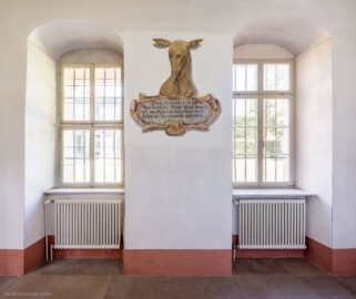 Schloss und Schlossgarten Schwetzingen - Schloss - Nordflügel, Nord-Süd-Teil - Gang zur Schlosskapelle, Westwand - Von Osten - Blick auf die Westwand des Gangs und auf ein Gemälde zur Erinnerung an eine Jagd am 17. September 1718, bei der Heinrich von Hessen-Darmstadt (1674–1741) einen Siebzehnender erlegte; Inschrift: "Den 17. Septembr. 1718 haben Ihro Hochfürstl. Durchl. Prinz Hennerich von Darmstatt diesen Hirsch von 17 Enden am Premmersuhl geschossen" (aufgenommen im Juni 2023, am späten Vormittag)