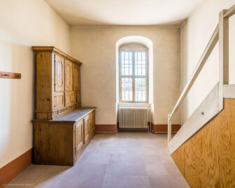 Schloss und Schlossgarten Schwetzingen - Schloss - Nordflügel, Nord-Süd-Teil - Schlosskapelle - Sakristei - Von Westen - Blick nach Osten in die ehemalige Sakristei; links ein Sakristeischrank (Datierung unklar, evtl. aus der Erstausstattungszeit9, rechts der Treppenaufgang zur Kanzel (um 1805 nachträglich angebaut) (Schlosskapelle: Länge ca. 14 Meter, Breite ca. 10 Meter, Höhe: bis unter das Dach, Achsen: 6, Eingang: Ostseite; Bauzeit: zwischen 1698 und 1715; Architekten: Johann Adam Breunig, Simon Sarto; Umbau innen im klassizistischen Stil: 1804-1806, Architekt: Friedrich Weinbrenner)  (aufgenommen im Juni 2023, um die Mittagszeit)